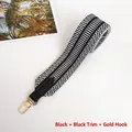 Detail of black and white geometric woven guitar strap with gold metal hooks - Gold Hook / Black + Black Leather
