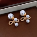 Detail of gold bow earrings featuring large white pearls on a brown leather surface - Gold Bowknot Pearl