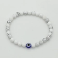 Close-up of white turquoise beaded bracelet with blue evil eye charm on elastic cord - Natural White Turquoise