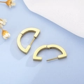 Dettaglio di orecchini a cerchio dorati a forma di D su una superficie celeste testurizzata - Stile Oro (KE99186-KFC)