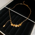 Dettaglio macro di una collana con ciondolo a moneta d'oro su vassoio in velluto nero - Collana