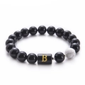 Macro shot of 10mm black onyx and white turquoise beads with golden letter B charm - Letter B