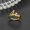 Macro shot of gold Aries zodiac ring featuring elegant cursive lettering on black texture - Adjustable Open / Aries Gold