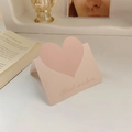 Pink heart-shaped cardboard card holder with Best Wishes text on a white desk - Mocha Coffee