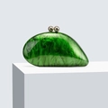 Green acrylic evening clutch bag with marble texture and golden sphere clasp on a pedestal - Green