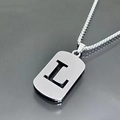 Macro shot of silver stainless steel dog tag pendant featuring a hollow letter L detail - L