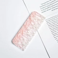Detailed view of pink acetate wide-tooth comb with marble texture on paper backdrop - Sakura Pink Terrazzo