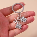 Détail du porte-clés de Noël argenté avec flocon de neige, cadeau et clochettes - Flocon de Neige/Boîte Cadeau/Cloche