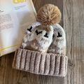 Close-up of thick knit beanie featuring a brown faux fur pompom on a wooden background - M (55-59cm) / Khaki