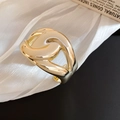 Close-up of polished gold chunky chain crossover ring on white silk background - Gold Cross Style