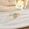 Macro detail of gold ring featuring a blue square gemstone surrounded by clear crystals - Blue Square Rhinestone Halo (JZ0126)