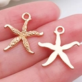 Pair of gold starfish charms for DIY jewelry making shown on a fingertip for scale - Sea Star Pendant 18x17mm