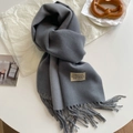 Grey cashmere-like knit scarf with fringe and minimalist brand label on white surface - Medium Grey
