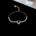 Detail of adjustable gold bracelet featuring a green heart zircon and sparkling accents - 18# Gold Green Heart Slider Style