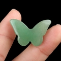 Polished green aventurine quartz butterfly carving held by hand on black background - Green Aventurine