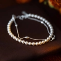 Dettaglio del bracciale a doppio strato con perle bianche e catena d'argento lucida - Design a Doppio Strato / Bianco Argento