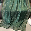 Green silk-like scarf with paisley pattern draped on a sofa for beach protection - Green