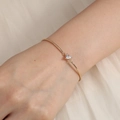Elegant gold metal bangle featuring a central heart-shaped cubic zirconia on a female wrist - Heart Zircon