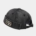 Close-up of black washed denim brimless docker cap with metal buckle and embroidery - Black