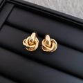 Macro shot of gold-plated twisted metal knot earrings on a black jewelry display stand - Metal Knot Stud Earrings with 925 Sterling Silver Earring Post / Gold