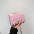Detailed close-up of pink V-stitch crossbody bag with gold chain strap and turn-lock - Pink