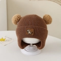 Detail of baby winter knit hat with double pom-poms and cute dinosaur patch - Dinosaur Label - Brown