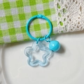 Blue pentagram acrylic keychain with a blue bell on a decorative fabric background - Transparent Blue