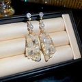 Dettaglio di orecchini geometrici con cristalli e perle su supporto di velluto - Oro-Bianco