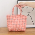 Detailed shot of quilted red gingham tote bag with blue bow embroidery and dual handles - Red Grid with Bow