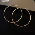 Nahaufnahme eleganter goldener Creolen auf einem schwarzen Tablett mit glattem Metall - Extra Große Goldene Creolen Stecker