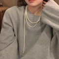 Gros plan d'un collier de perles long vintage multicouche avec pendentifs dorés - Collier de perles coeur double couche