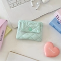 Close-up of mint green quilted coin purse with snap button on a desktop with accessories - Mint Green