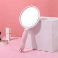 Tragbarer rosa Handspiegel mit niedlichem Cartoon-Gesicht Relief und geriffeltem Griff - Nordisches Rosa