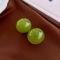Detail view of round green resin earrings on brown velvet with vintage props - Green