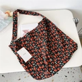 Close-up of black corduroy tote bag with red floral pattern and brand label - Kerria Red