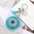 Makro-Detail von Evil Eye Anhänger mit blauen Steinen, weicher Quaste und silberner Glocke - Seeblaues Rundauge Silberner Verschluss