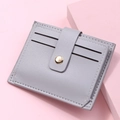 Close-up of litchi texture on slim accordion card holder with golden snap closure - Gray