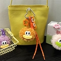 Close-up of fuzzy cartoon plush charms with heart metal clasp on a leather handbag - Orange Red