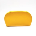 Dettaglio di una trousse gialla con pelle testurizzata e cerniera superiore curva elegante - Giallo