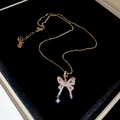 Dettaglio della collana con ciondolo a farfalla dorata e pietre lucenti in astuccio - Collana con ciondolo a farfalla / Oro