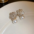 Macro shot of gold flower earrings with crystals and pearls on white ceramic plate - Rhinestone Inlaid Pearl Stud / Gold