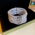 Detail eines mehrlagigen weißen Perlenarmbands mit silbernem Strassverschluss auf Samt - Mehrschichtiger Perlen-Strass-Stil / Weiß