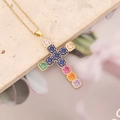 Primo piano di una collana dorata con pendente a croce e zirconi multicolore - Blu Colorato
