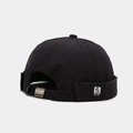 Detalle de gorro docker negro con correa ajustable, hebilla metálica y etiqueta de letra S - Negro