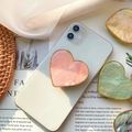Supporto per telefono a cuore in marmo rosa con bordo dorato su uno smartphone bianco - Impugnatura Cuore Oro / Conchiglia di Capasanta Rosa