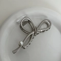 Detail view of silver metal bow hair claw clip with a single pearl on ceramic tray - Grey Silver - Bow (with Pearl)