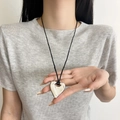 Polished silver heart pendant necklace with black cord cord shown in hand for scale - Silver Hollow Heart