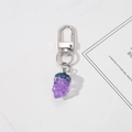 Gros plan d'un porte-clés raisin en résine violette avec mousqueton en métal argenté - Raisins
