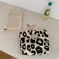 Close-up of leopard print canvas tote bag on a desk with lifestyle accessories - Leopard Print Makeup Bag