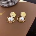 Dettaglio di orecchini vintage con disco dorato e grande perla bianca su pelle marrone - Stile Perla con Piastra Rotonda Martellata / Perla artificiale / Oro